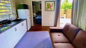 A compact living space with a kitchenette, a sofa, a bed, and a large window.