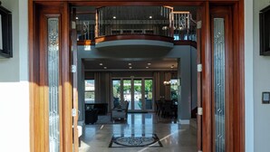 A spacious foyer with a polished marble floor, a central decorative rug, and a glass door leading to a balcony. - Sunset Manor: Luxury Wine Country Estate; Pool, Views, Steps to Wilson Creek (Temecula)