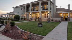 A large, two-story building with a covered patio area, multiple balconies, and a well-maintained lawn. - Sunset Manor: Luxury Wine Country Estate; Pool, Views, Steps to Wilson Creek (Temecula)