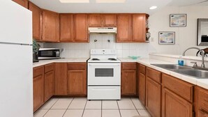Una cucina con mobili in legno, un fornello bianco e un forno a microonde.