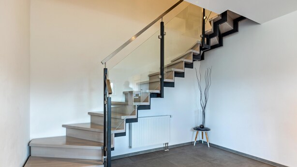 Una escalera moderna con barandillas de vidrio y diseño minimalista.