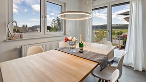 Comedor con mesa, sillas, una botella de champán y vistas al exterior.