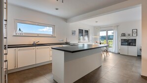 Una cocina moderna con una isla central, armarios blancos y ventanas amplias.