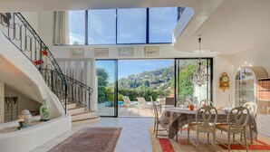 A spacious interior with a staircase, dining area, and large windows offering a view of the outdoors. - Semiramis Villa Laurie - Private pool, Mougins, France (Mougins)