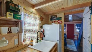 A compact kitchen with wooden cabinets, a white sink, and a refrigerator. - Cozy & rustic Tiny House in Downtown Leadville (Leadville)