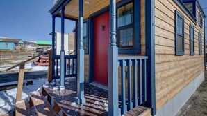A wooden cabin with a red door, blue railings, and a porch. - Cozy & rustic Tiny House in Downtown Leadville (Leadville)