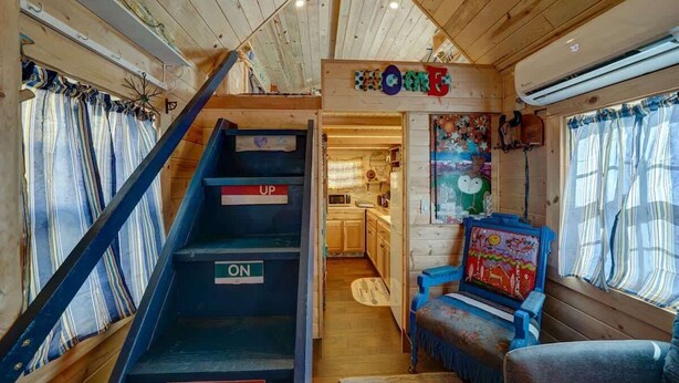 A cabin interior with a wooden staircase labeled "UP," "ON," and "COME," leading to a kitchen area. - Cozy & rustic Tiny House in Downtown Leadville (Leadville)