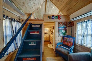A cabin interior with a wooden staircase labeled "UP," "ON," and "COME," leading to a kitchen area. - Cozy & rustic Tiny House in Downtown Leadville (Leadville)