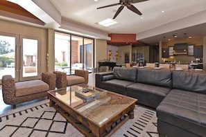 A spacious living room with a large sofa, a coffee table, and a piano. - New! Stunning Modern Desert Retreat (Bermuda Dunes)