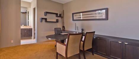 A dining area with a dark wood table, beige chairs, and a ceiling fan.