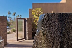 A stone wall with a reflective surface, a glass door, and a building in the background.