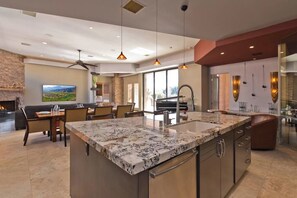 A modern kitchen with a large island, built-in appliances, and pendant lighting.