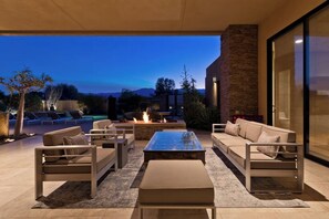 An outdoor patio with a fire pit, sofas, and a coffee table. - New! Stunning Modern Desert Retreat (Bermuda Dunes)