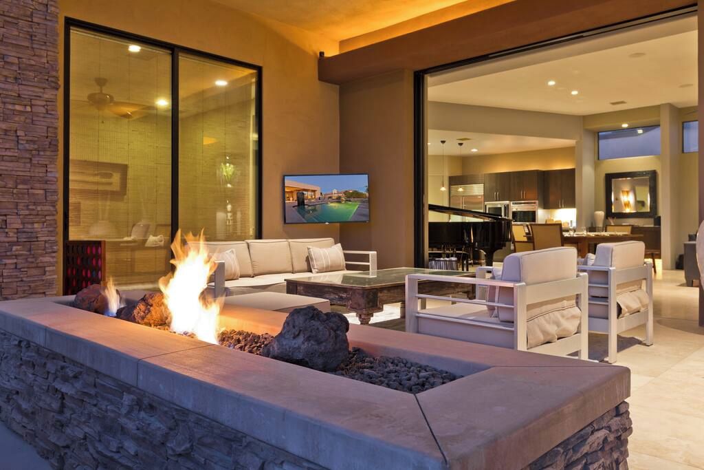 A modern living room with a stone fire feature, comfortable seating, and a television mounted on the wall.