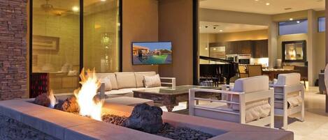 A modern living room with a stone fire feature, comfortable seating, and a television mounted on the wall.