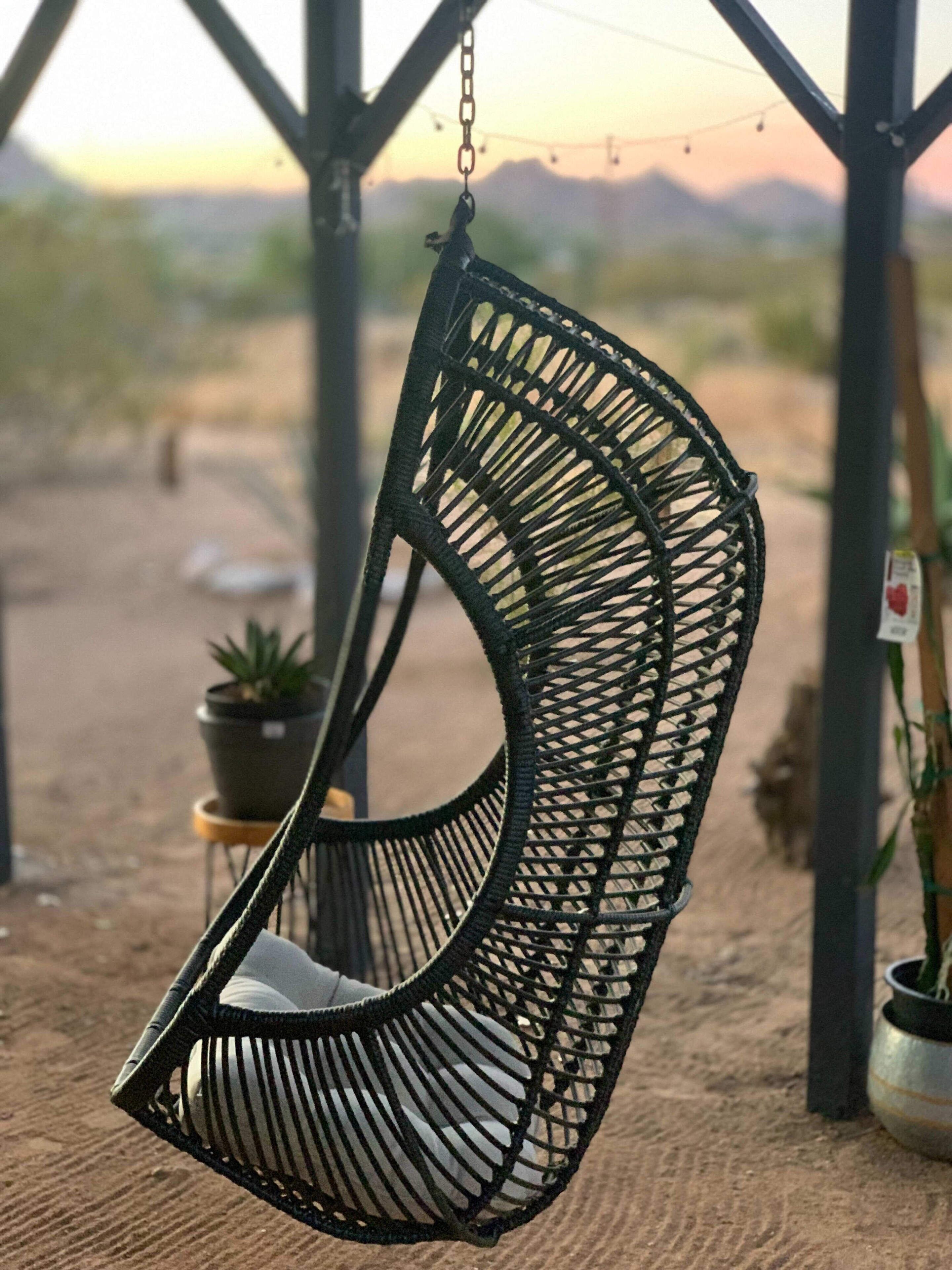 A black hanging chair with a woven design, suspended from a metal frame.