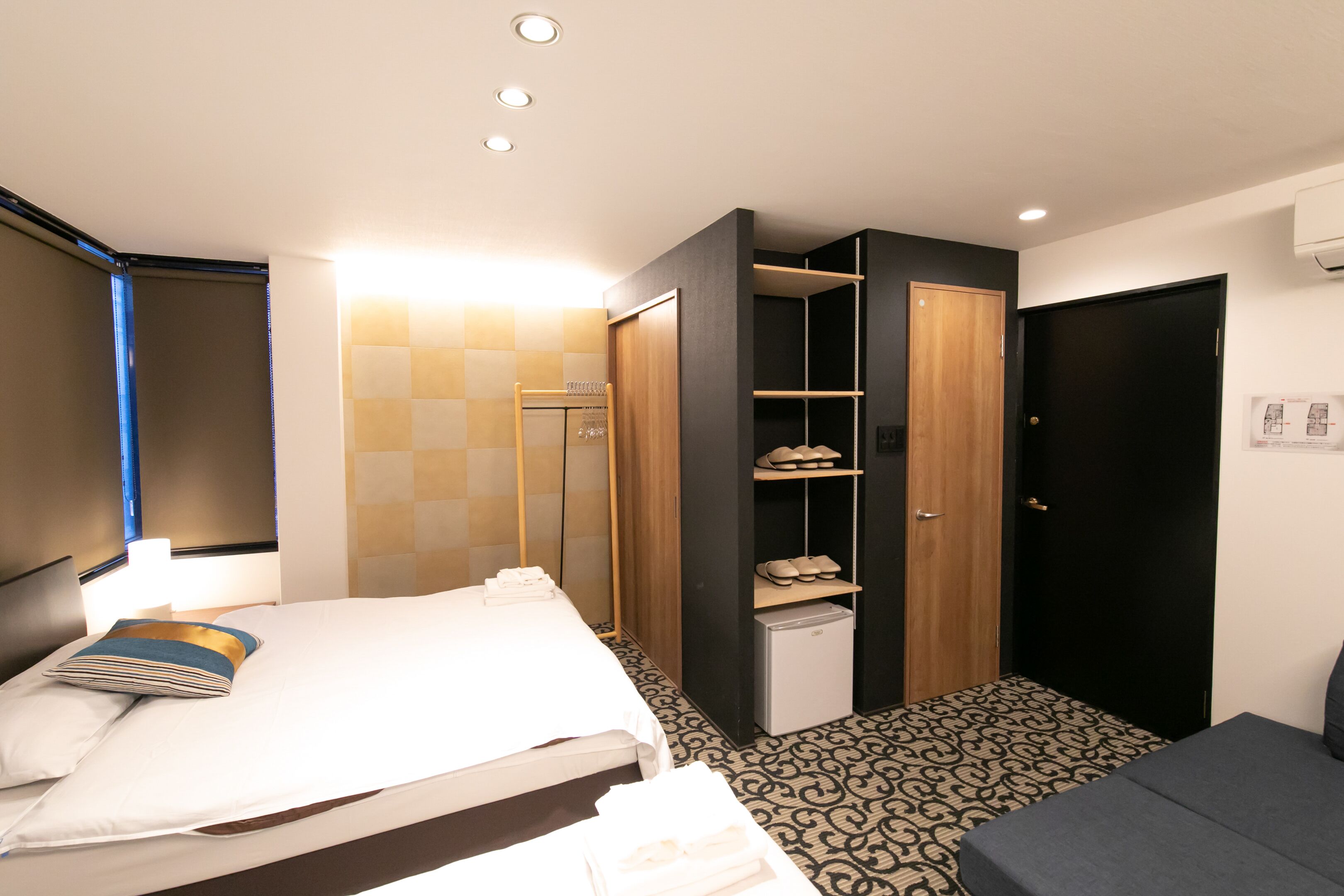 A hotel room with a bed, a wardrobe, a small desk, and a door.