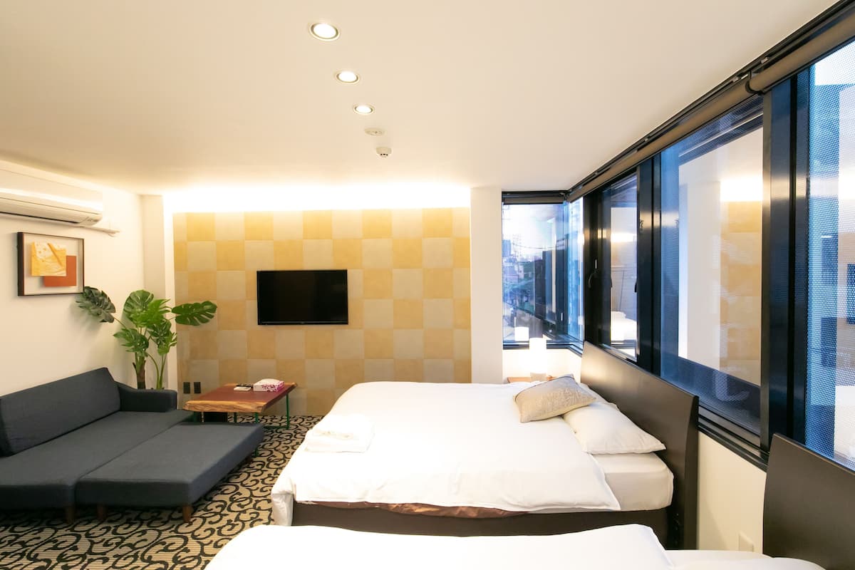 Ein Hotelzimmer mit Bett, einer Couch, einem Fernseher und einem großen Fenster.