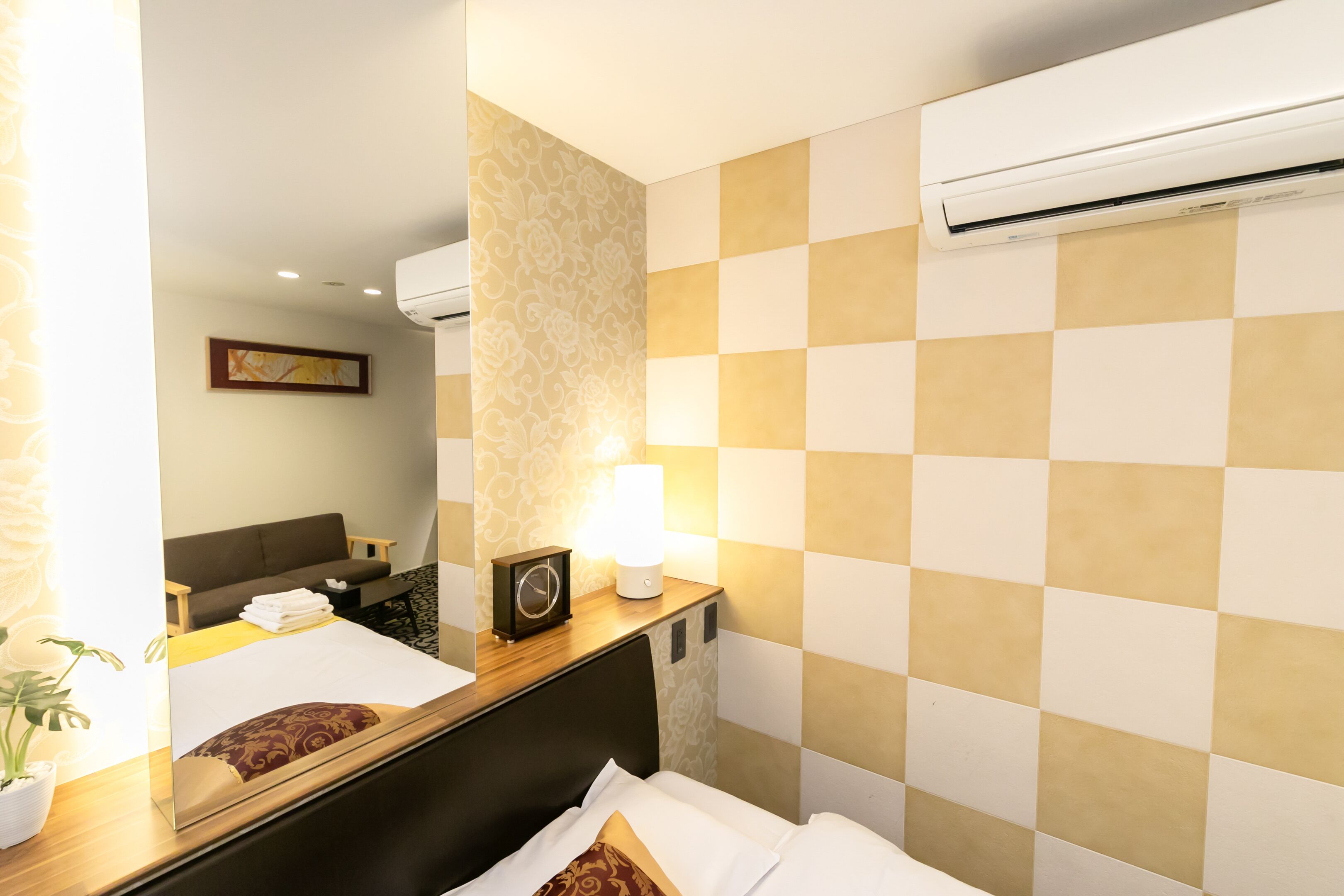 Ein Hotelzimmer mit Bett, Nachttisch, Lampe und Klimaanlage.