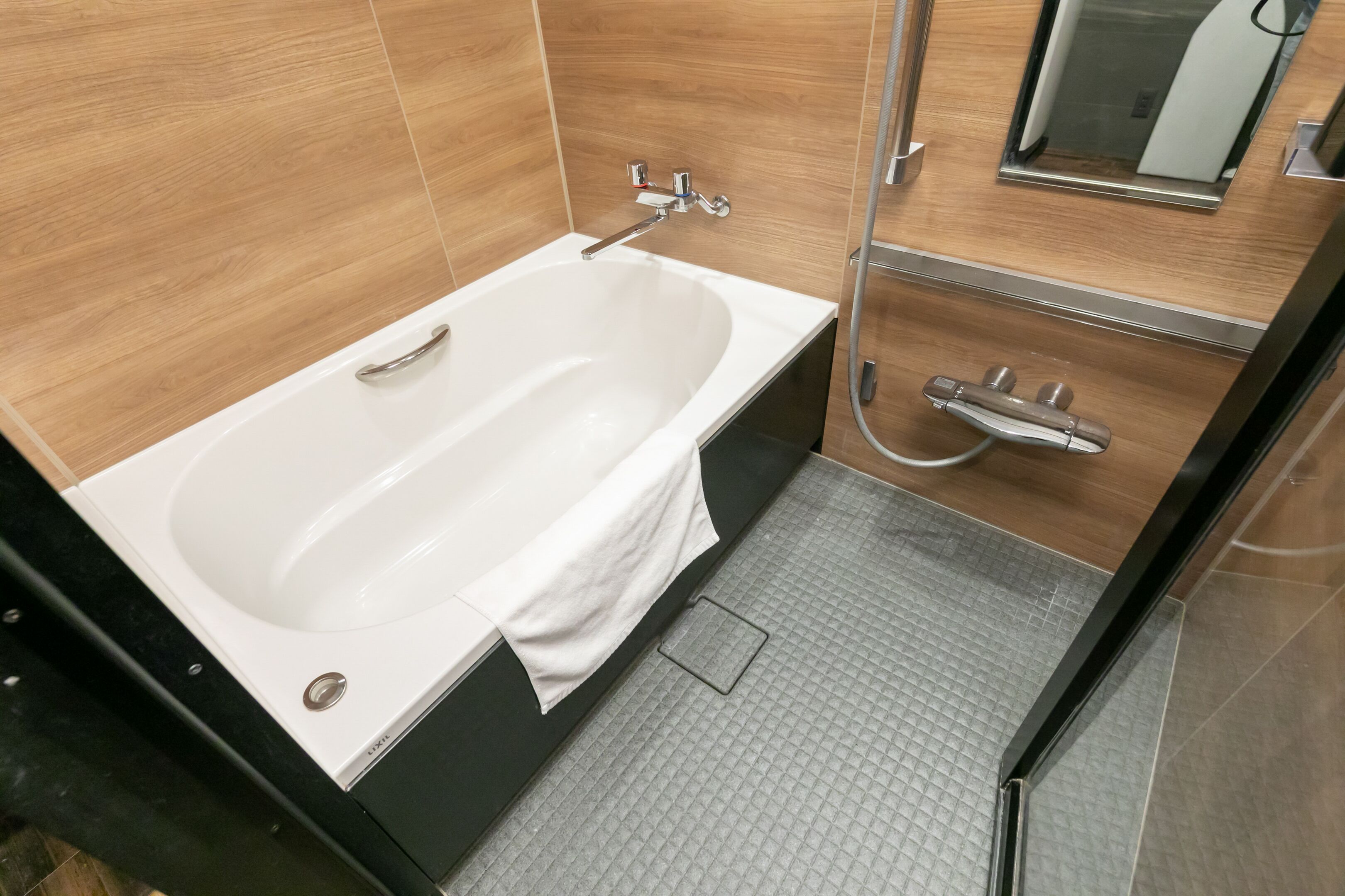 Un baño moderno con una bañera independiente, ducha con cabezal de mano y un espejo pequeño sobre el lavabo.