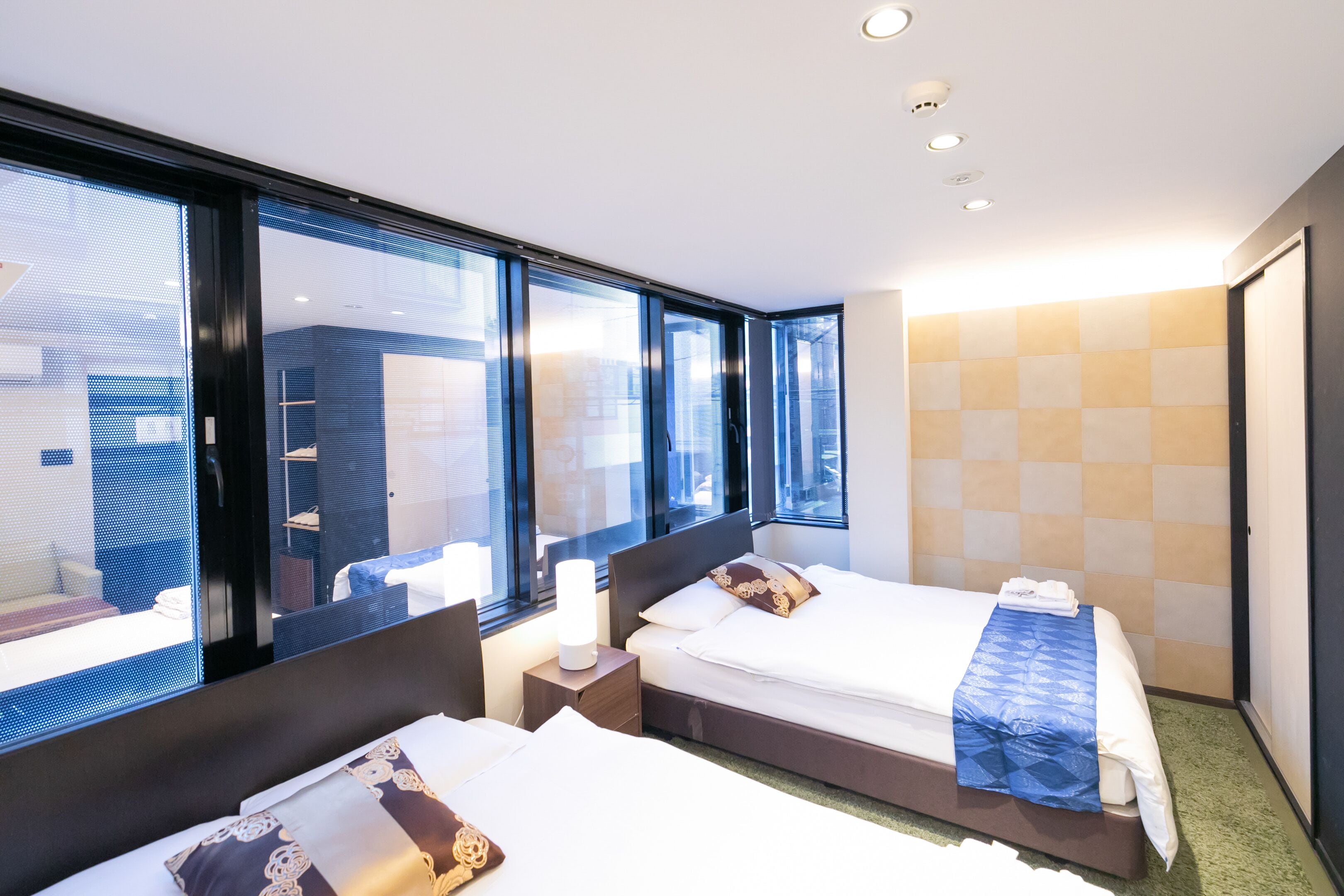A hotel room with two beds, large windows, and a view of the city.