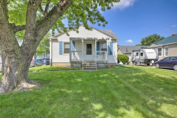 A single-story house with a front porch, a tree in front, and a trailer parked in the driveway. - Peaceful Speedway Retreat Near Downtown Indy (Speedway)