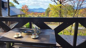 A wooden deck with a table set for tea, overlooking a scenic landscape with trees and mountains. - A high-quality plateau life like your own home ... A natural hot spring flowing, one private plateau villa (仙北市田沢湖生保内下高野)
