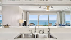 Eine Küche mit einem doppelten Spülbecken, einem Deckenventilator und Blick aufs Meer.