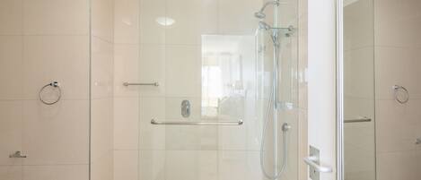 Un baño moderno con cabina de ducha de vidrio, barandilla y suelo de baldosas.