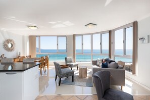 A spacious living area with a view of the ocean, a dining area, and a kitchen. - Ocean View A1101 by CTHA (Cape Town)