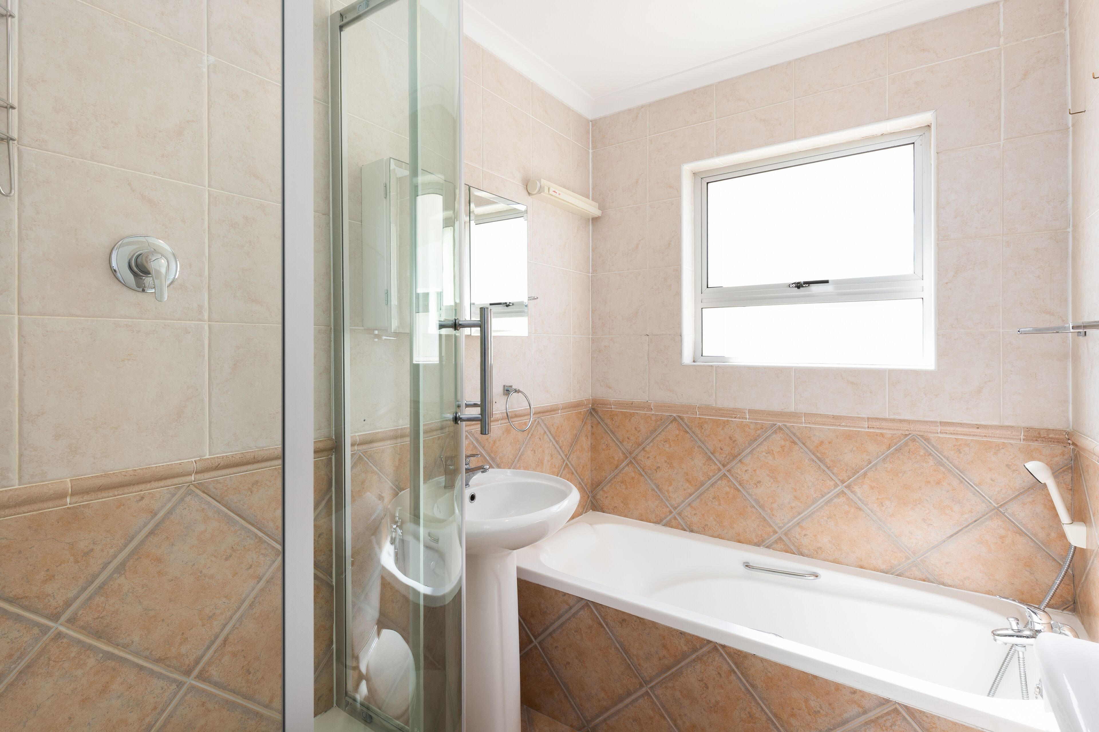Un bagno moderno con box doccia in vetro, un lavabo e una vasca da bagno.