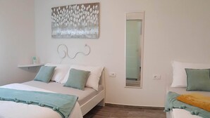Een slaapkamer met twee bedden, een nachtkastje, een spiegel en een kunstwerk aan de muur.