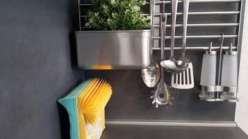 Une cuisine équipée d’appareils électroménagers en acier inoxydable, avec des ustensiles suspendus et une plante en pot.