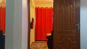 A hallway with a wooden floor leading to a room with a red curtain and a door with a decorative panel. - South B 1 bedroom rental furnished apartment  (Nairobi)
