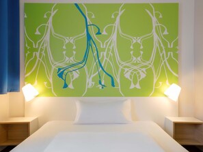 A hotel room with a bed, two bedside tables, and a green abstract wall art. - B&B Hotel Paderborn (Paderborn)