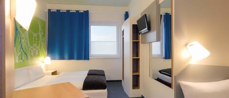 A hotel room with a bed, a desk, a chair, a TV, and a mirror.