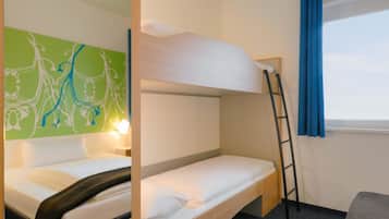 A bunk bed room with a ladder, a desk, and a window with blue curtains.