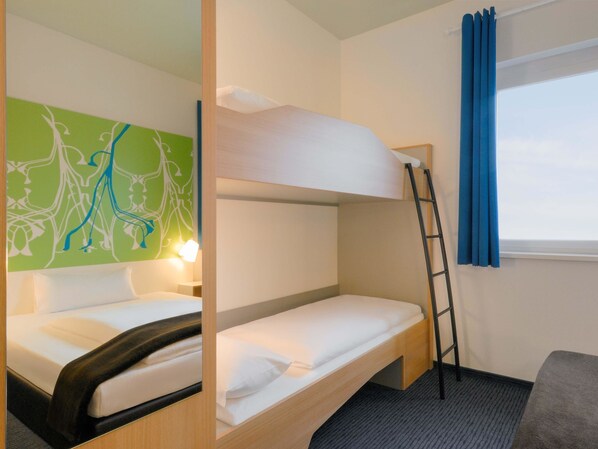 Habitación con literas, una escalera, escritorio y ventana con cortinas azules.