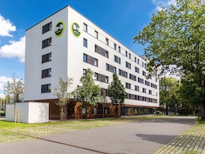 Un hôtel-chambre d’hôtes moderne avec une façade blanche, de nombreuses fenêtres et une cour dallée.