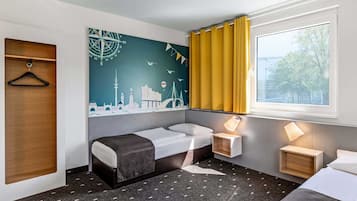 Habitación de hotel con cama, sofá, escritorio, estante en la pared y ventana con cortinas.