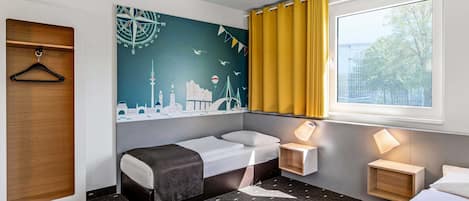 A hotel room with a bed, a sofa, a desk, a wall-mounted shelf, and a window with curtains.