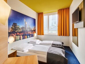 A hotel room with two beds, a large window with orange curtains, a cityscape mural on the wall, and a flat-screen TV mounted on the wall. - B&B Hotel Frankfurt-Hbf (Frankfurt)