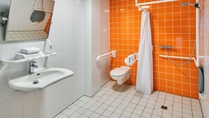 A bathroom with white and orange tiles, a sink, a toilet, a shower with a curtain, and a mirror.