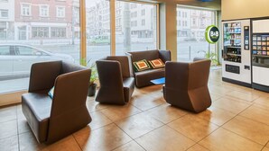 A hotel lobby with modern seating, large windows, and vending machines.