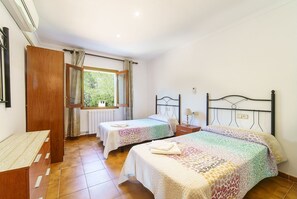 Two single beds with matching headboards and nightstands, each with a lamp, are complemented by a wardrobe and a small table.