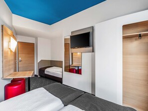 A modern hotel room with a bed, a desk, a TV, and a wardrobe. - B&B Hotel Hamburg City-Ost (Hamburg)