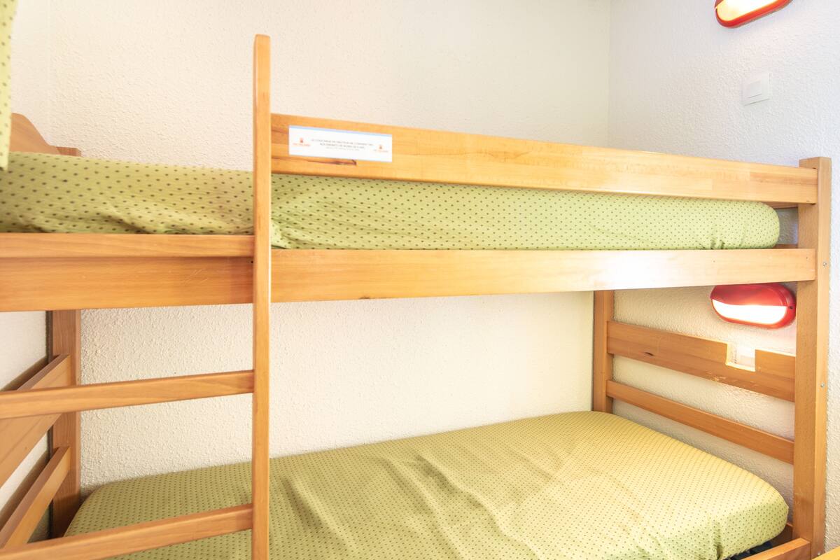 Ein Stockbett mit einer grün gepunkteten Matratze und einem Holzrahmen.