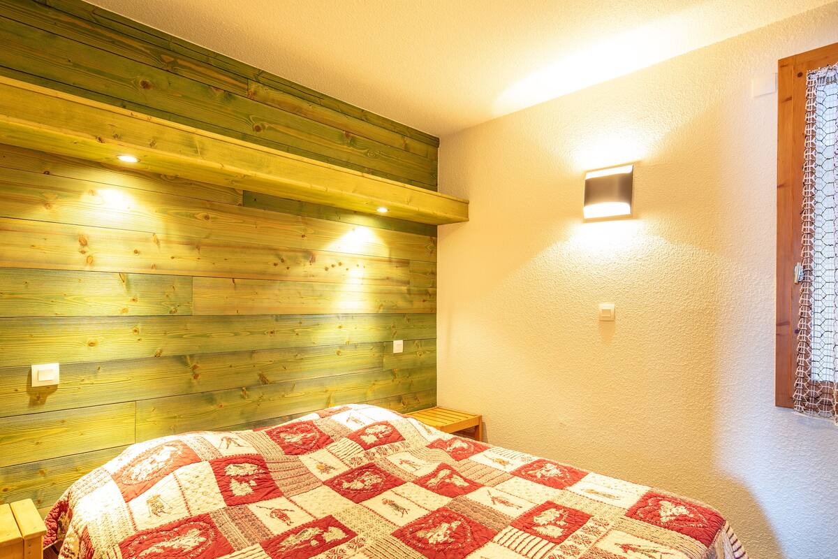 Ein Schlafzimmer mit einem Holz-Kopfteil, einer gesteppten Bettdecke und zwei Nachttischlampen.