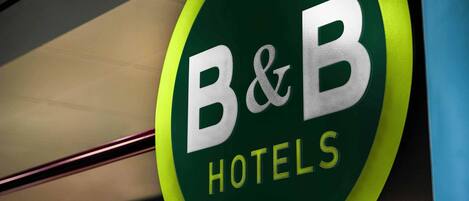 A close-up of a B&B Hotels sign with a green and yellow color scheme.