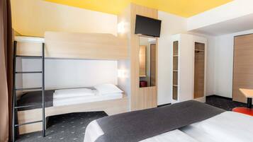 Ein Hotelzimmer mit Etagenbett, Schreibtisch mit Stuhl, Kleiderschrank und Fernseher.